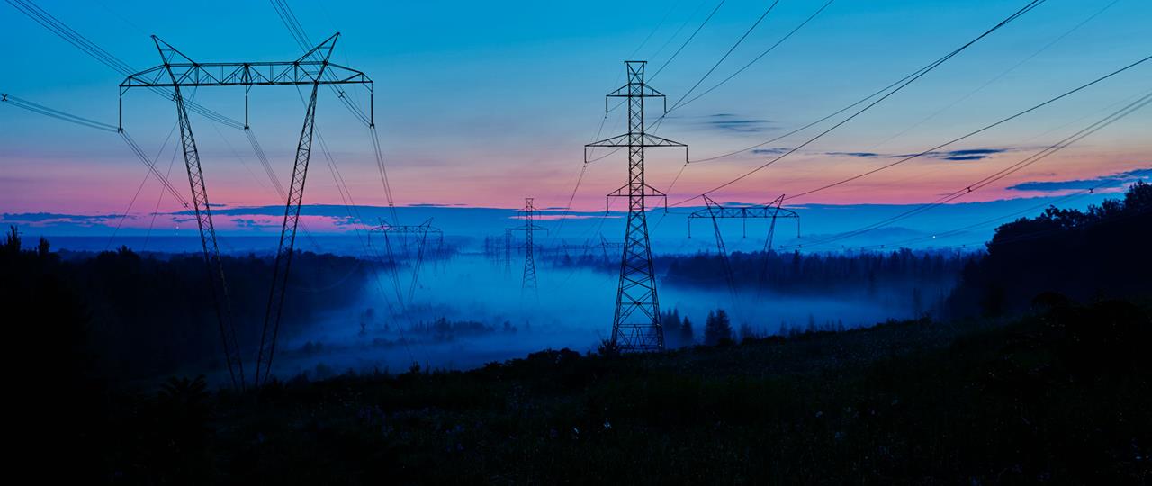 sunrise with a blue and pink skies overlooking a field with transmission lines